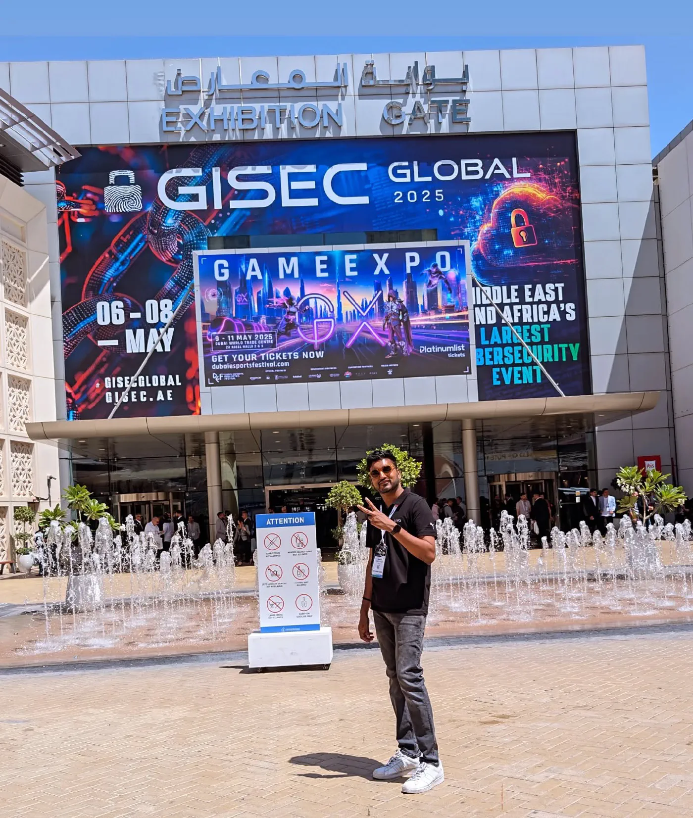 A man standing in front of the Dubai World Trade Centre exhibition gate beneath a huge digital banner reading GISEC GLOBAL 2025, Middle East and Africa's largest cybersecurity event, with rows of fountains along the plaza.
