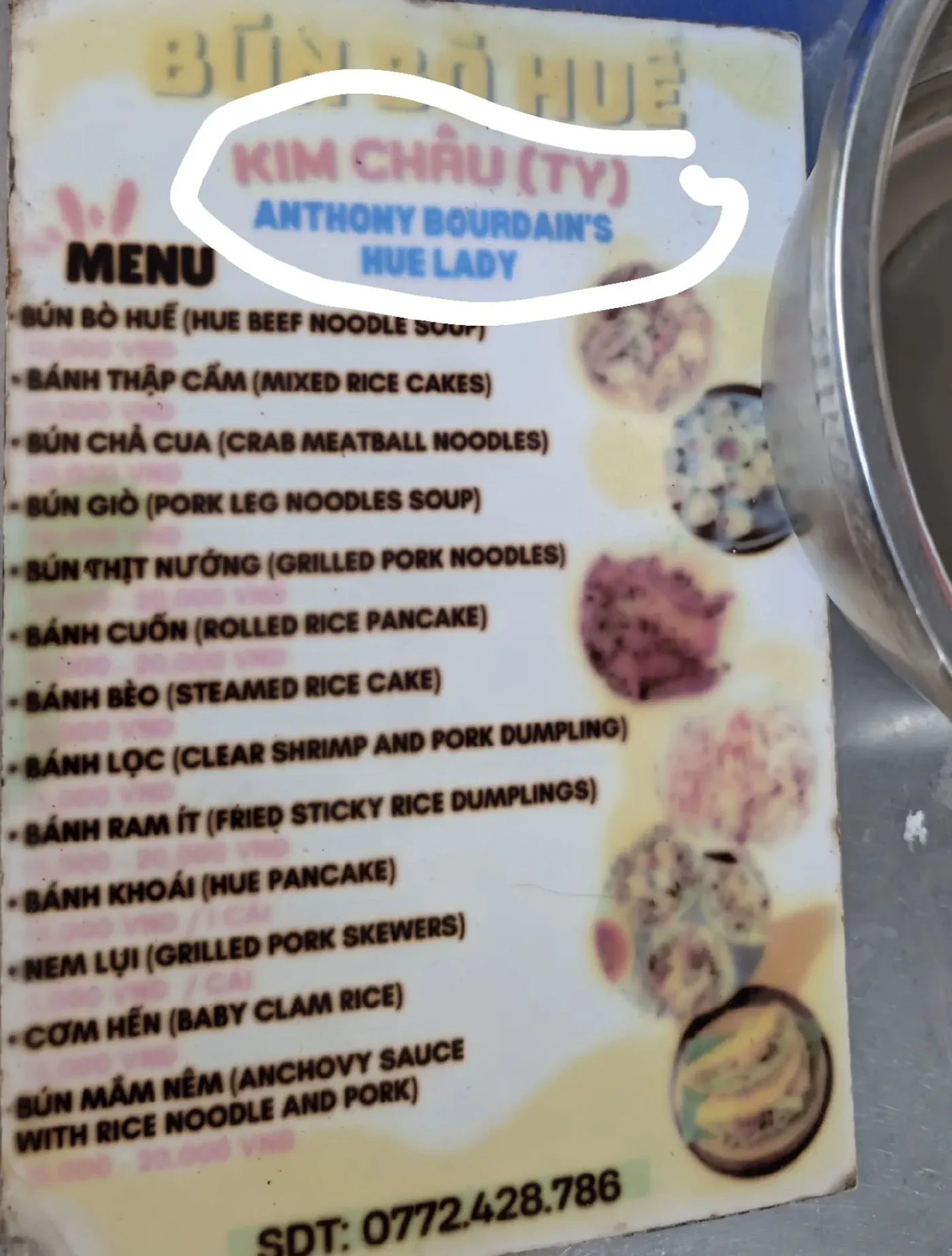 A weathered laminated menu board for a Vietnamese street stall reading BÚN BÒ HUẾ, with the name Kim Châu and the line Anthony Bourdain's Hue Lady circled in white, above a list of Huế dishes.